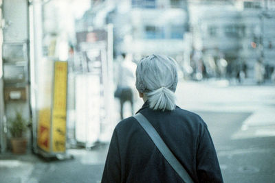 Rear view of woman standing on street in city