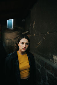 Portrait of young woman standing by wall