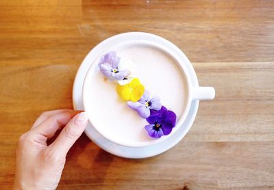 Close-up of hand holding ice cream in bowl on table