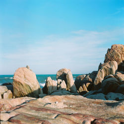 Rocks on beach against blue sky