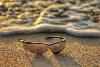 Close-up of sunglasses on sand at beach