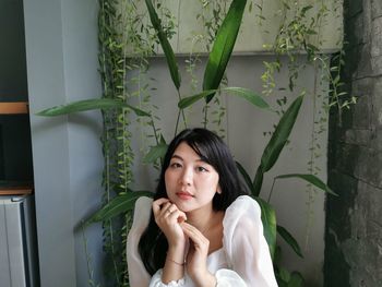 Young woman sitting against plants