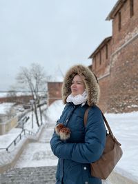 Portrait of smiling young woman standing on snow