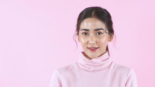 Portrait of woman against pink background