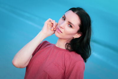 Portrait of smiling young woman against blue sky