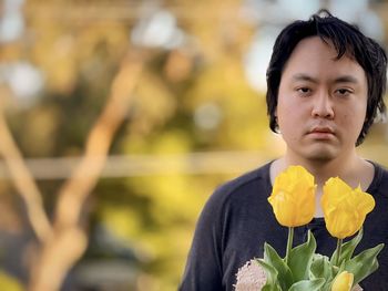 Portrait of young man against yellow flowering plants