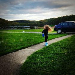 Rear view of woman with umbrella on road against sky