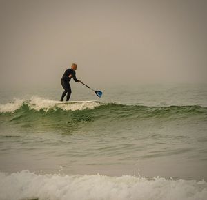 Man surfing in sea against sky at beach