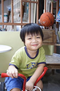 Cute smiling boy sitting on tricycle at home