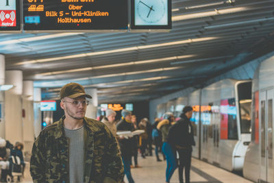 Man in camouflage jacket standing at railroad station