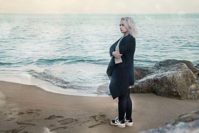 Full length of young woman standing on beach