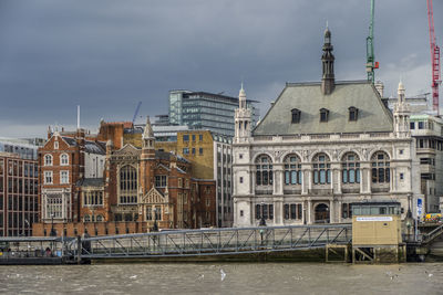 Buildings at waterfront against cloudy sky