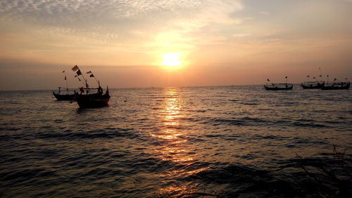 Silhouette sailboat in sea against sky during sunset