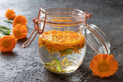 Close-up of orange flowers in glass jar on table