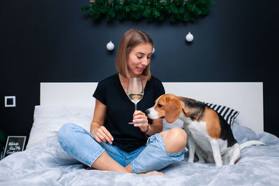 Young woman with dog sitting on bed