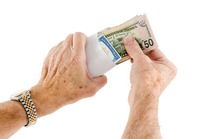 Close-up of hand holding hat against white background