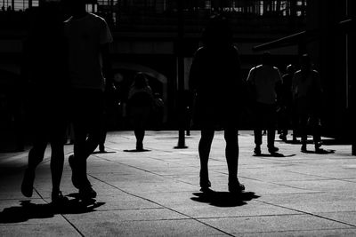 Rear view of people walking on sidewalk in city