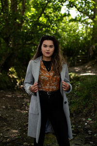 Portrait of smiling young woman standing against trees. can be used for promotion or advert. 