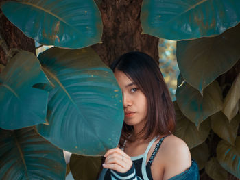 Portrait of young woman standing amidst leaves 