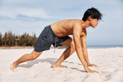 Full length of young woman exercising at beach