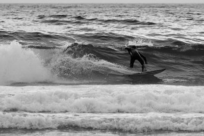 Man surfboarding on waves in sea