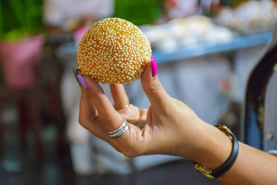 Cropped hand of woman holding sweet food outdoors