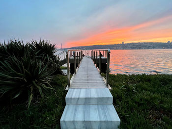 Pier amidst sea against sky during sunset