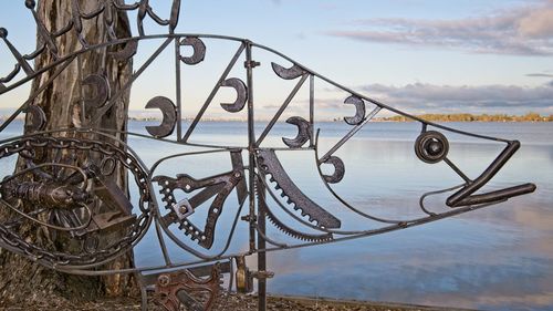 Close-up of text on railing by lake against sky