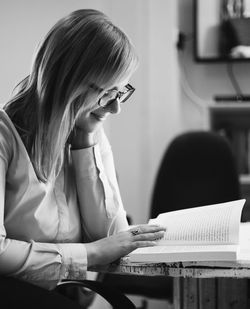 Young woman reading book on table