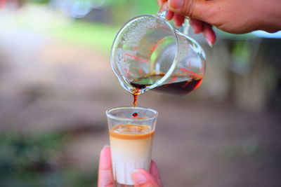 Close-up of person pouring a glass of coffee