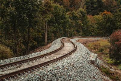 Railroad track curves near a forest on a overcast autumn day