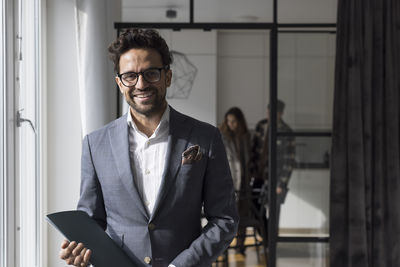 Portrait of happy male real estate agent holding folder at home