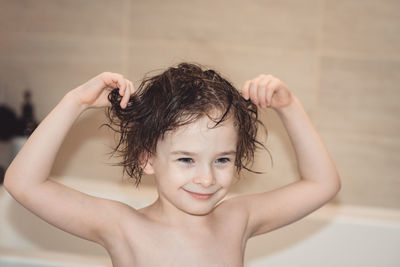 Smiling girl with wet tousled hair in the bathroom. the concept of childhood, happiness, hygiene