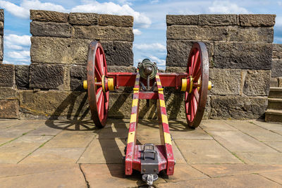 An antique cannon in red-yellow color on the walls of a medieval castle.