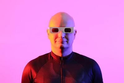 Portrait of young man wearing sunglasses against pink background