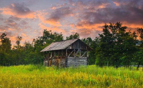 House on field against sky during sunset