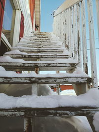 Snow covered staircase by building against sky during winter