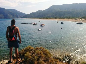 Rear view of shirtless man in sea against mountains