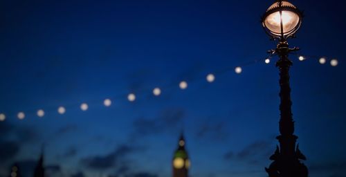 Low angle view of illuminated street light against blue sky