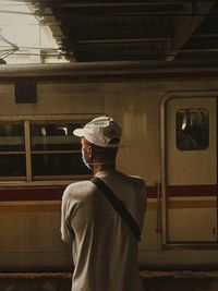 Rear view of man standing at railroad station