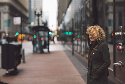 Woman standing on sidewalk in city