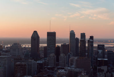 Modern buildings in city against sky during sunset