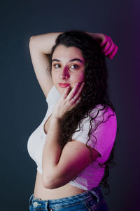 Profile of young woman wearing white shirt with one hand on her head and the other on her chin. 