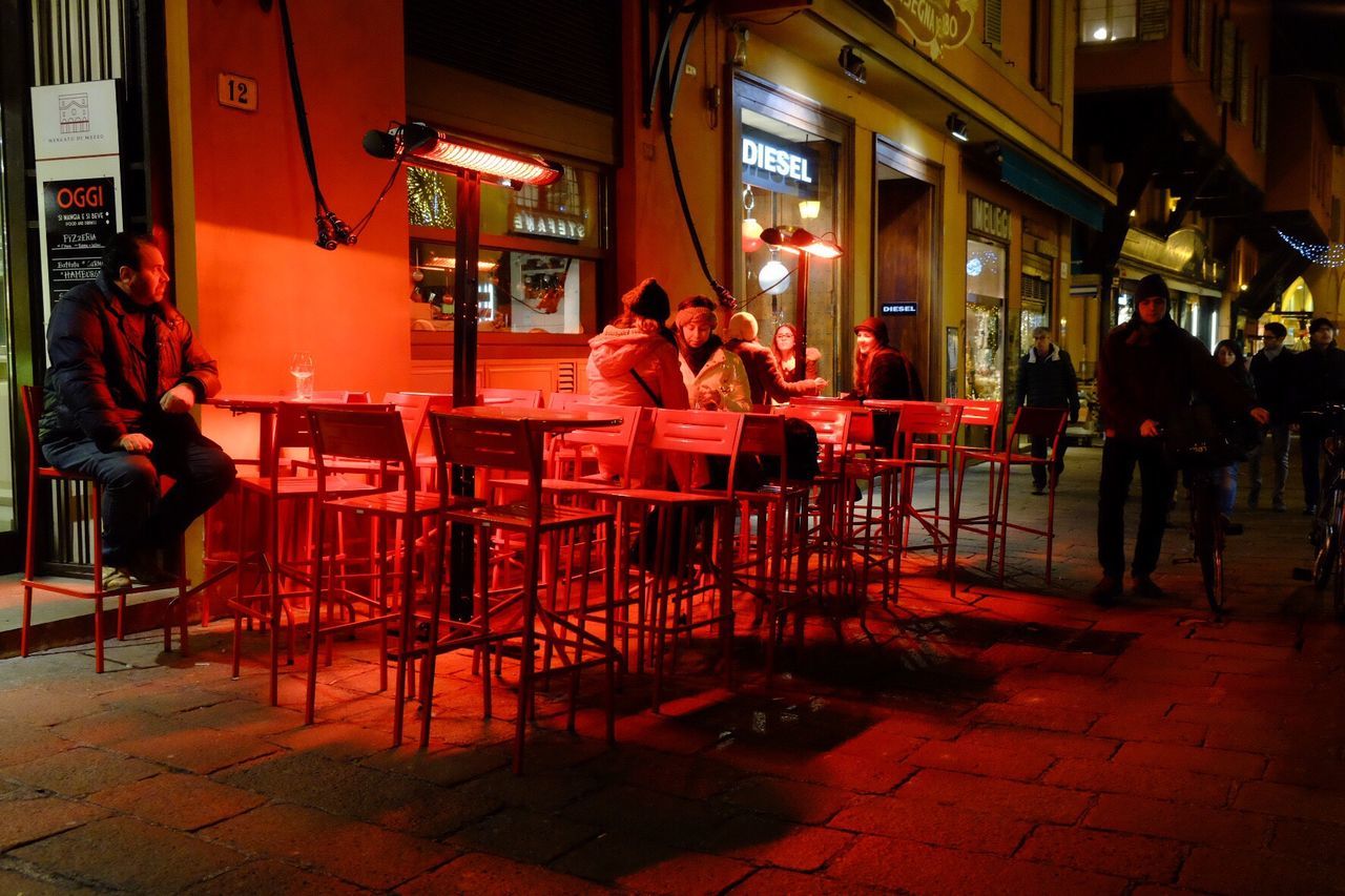 lifestyles, indoors, leisure activity, men, person, sitting, illuminated, arts culture and entertainment, restaurant, casual clothing, standing, chair, communication, built structure, night, red, architecture, table