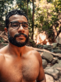 Portrait of shirtless man standing in forest