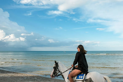 Man sitting at beach against sky