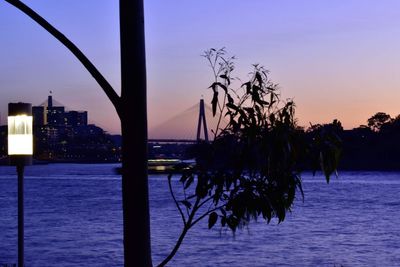 Silhouette bridge over sea against sky at sunset