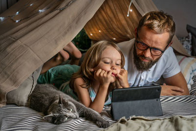 Father and son playing in a teepee tent at home.