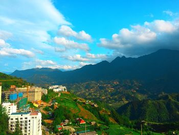 Scenic view of townscape and mountains against sky