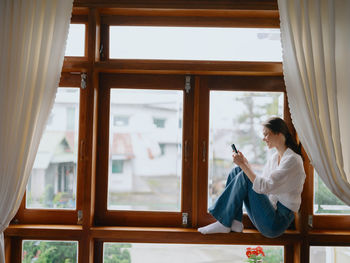 Side view of woman looking through window